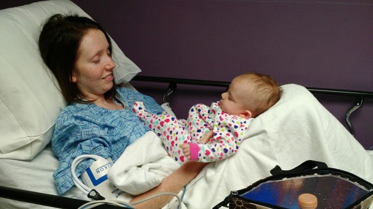 woman lying in hospital bed holding baby in her lap
