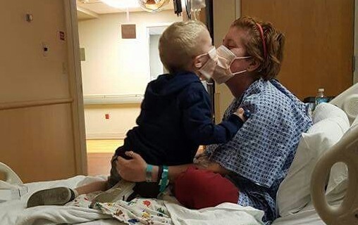 woman sitting in hospital bed kissing a child