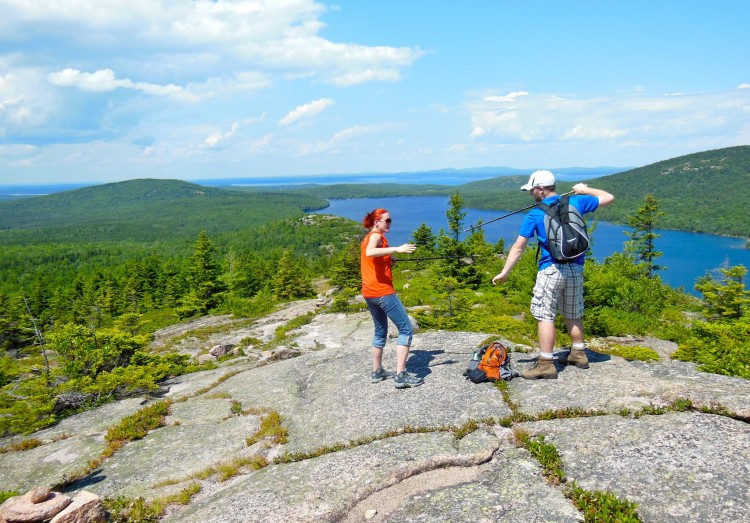 two people standing on top of mountain overlooking lake