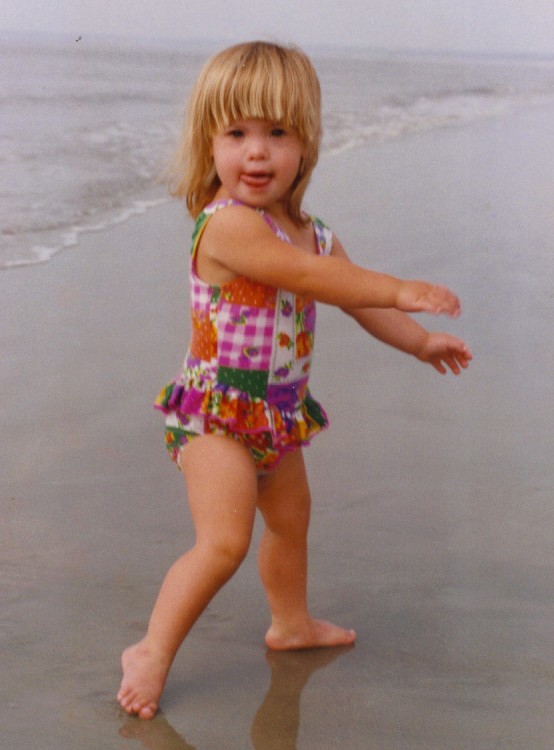 little blonde girl at beach in bathing suit