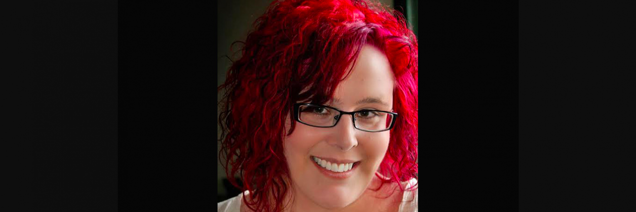 Portrait of contributor, a white woman wearing glasses, with red hair, and smiling