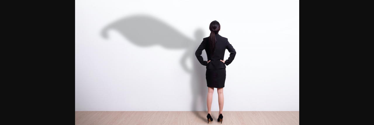 When I Look For a Hero, This Is Where I Look Now Woman in suit with her shadow showing a cape on the wall