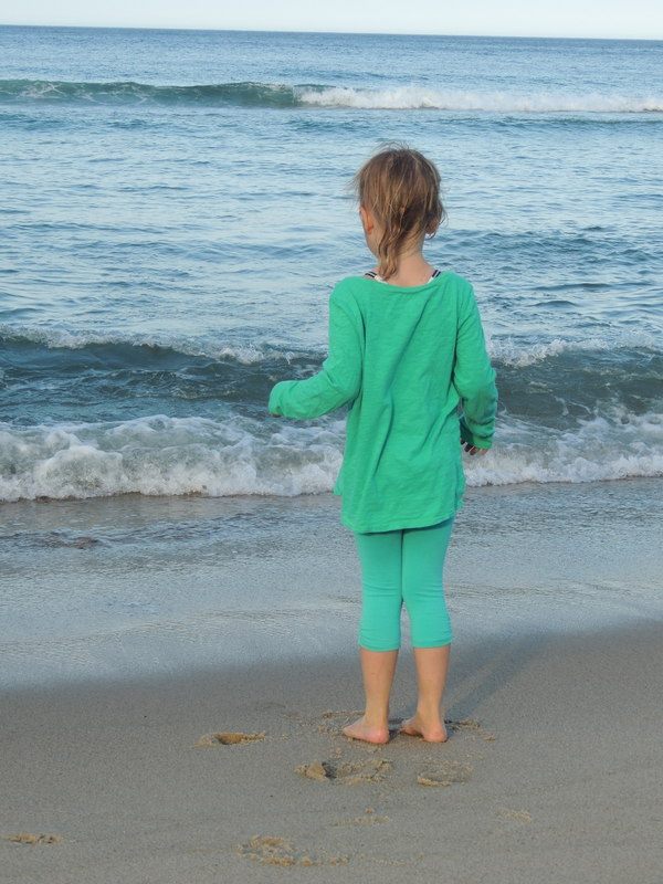 Girl standing on the shore near the ocean water