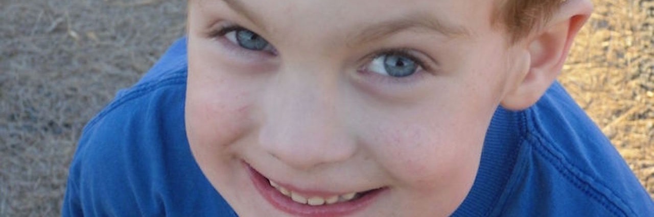 Parenting a Child Who Is in Between 'Healthy' and Chronically Ill little boy smiling and wearing a blue shirt