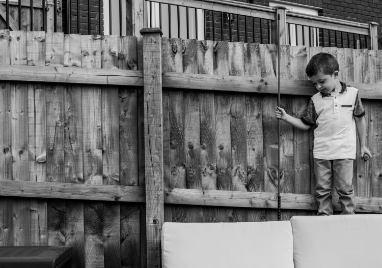 A young boy by a fence.