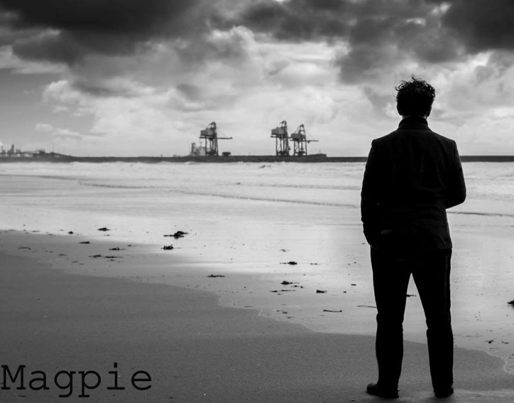 A photo of an adult man from behind on a beach. 