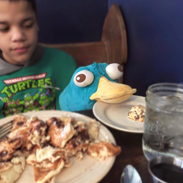 boy and stuffed animal sitting at restaurant table