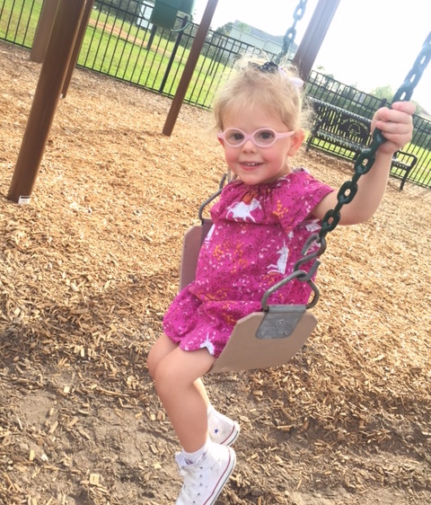 little girl in glasses on swing