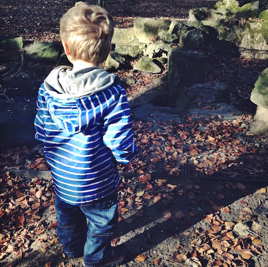 Boy in striped blue and white hoodie standing outdoors