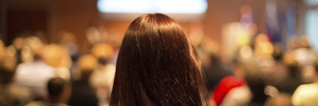 woman standing behind audience at conference hall