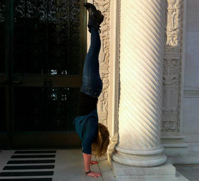 woman doing a handstand next to a column