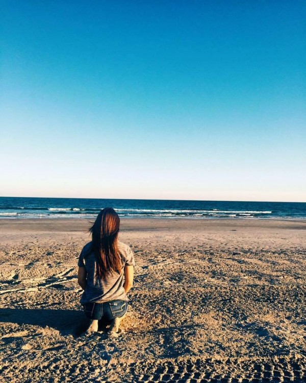 woman sitting on grass looking at ocean