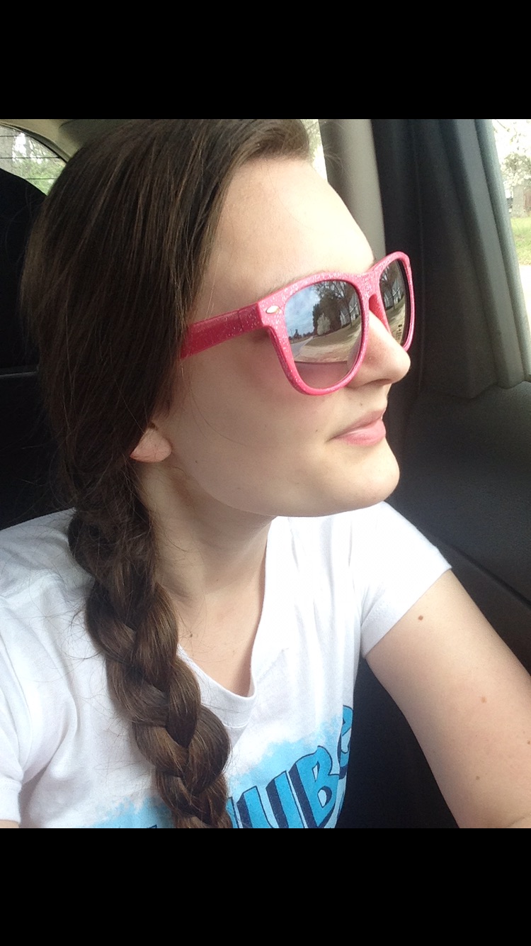 woman with a single braid wearing a white t-shirt and sunglasses