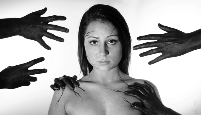 A woman stares into the camera. Black hands reach out to her.