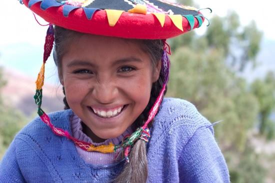 Girl in a colorful hat, smiling.