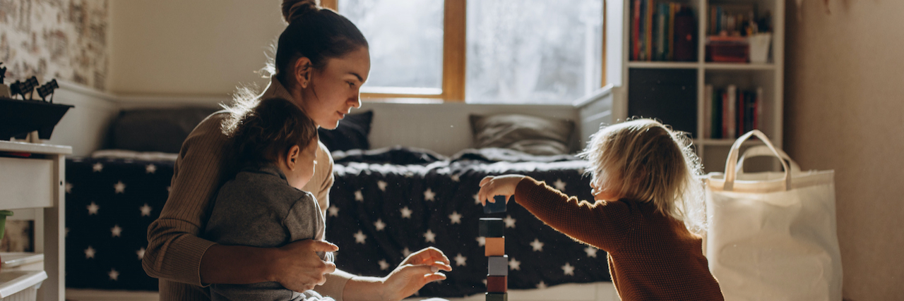 How to Advocate for Your Child with Growth Hormone Deficiency Mother playing with children while sitting on floor at home with wooden toys