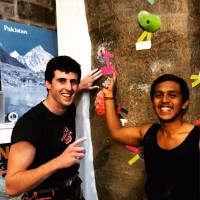 two men smiling in front of rock climbing wall