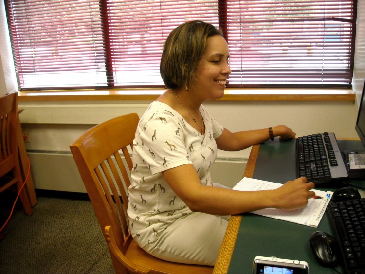 woman writing and typing on computer at college library