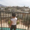 son standing on balcony looking at pool
