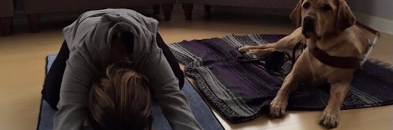 woman doing yoga beside guide dog