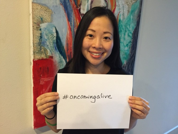 Sarah Shin holding "on coming alive" sign