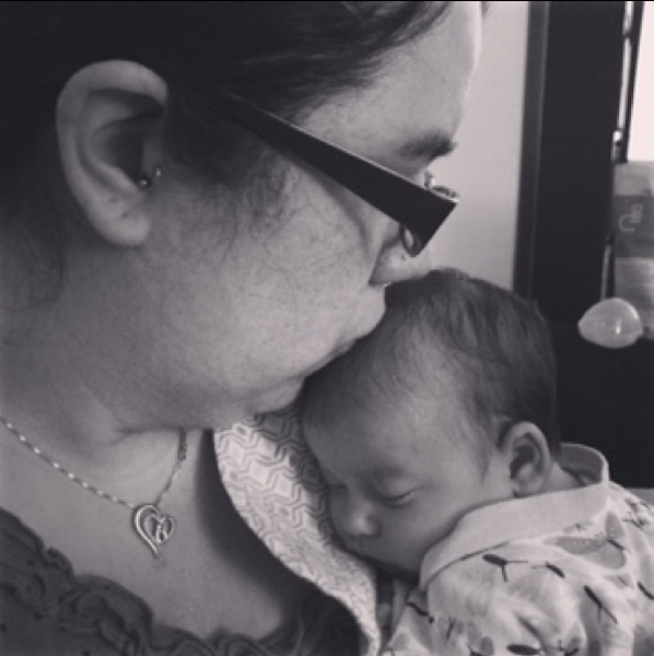 A black and white photo of Noel kissing her new born baby.
