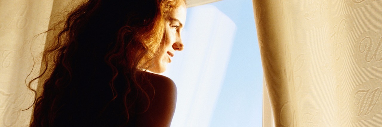 What I Wish I Knew Before My Crohn's Disease Diagnosis young woman smiling, looking out window