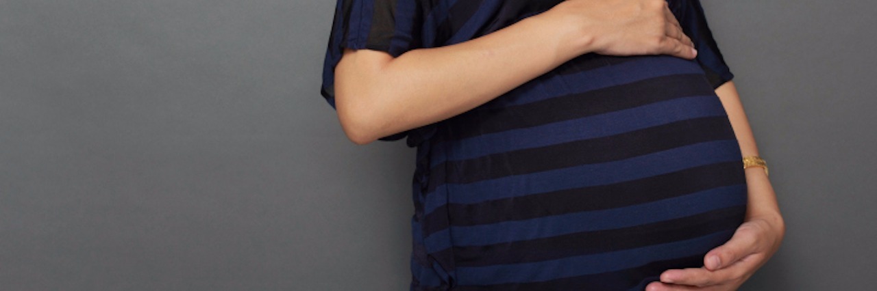 When I'm Called Selfish for Getting Pregnant When I Have a Disability pregnant woman holding her stomach