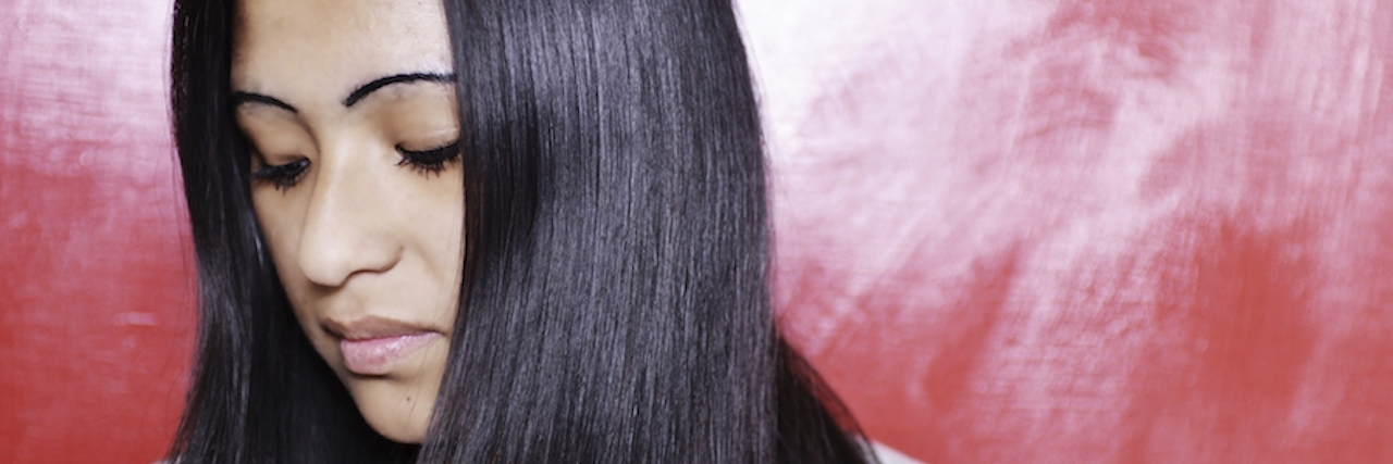 A Letter to the Man Who Implied My Friend Was 'Faking' Her Depression a profile picture of a young woman with long, dark hair looking down