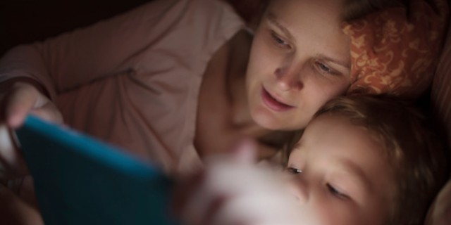 woman reading with child in bed