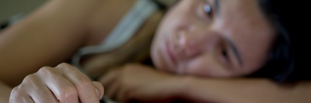 Closeup on hand of sad depressed woman sitting on sofa.