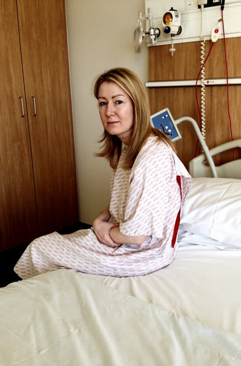 woman sitting on hospital bed wearing hospital gown