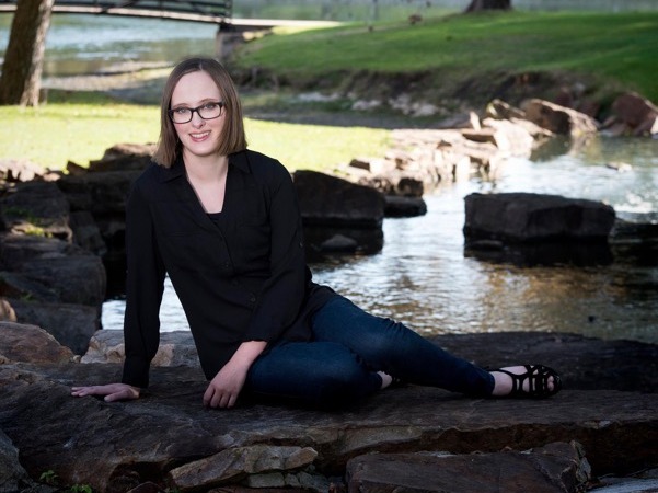 Woman sitting next to a pond in a park