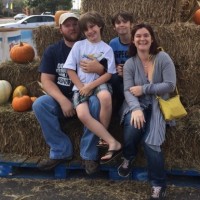 family of parents and two sons sitting on hay bales at halloween