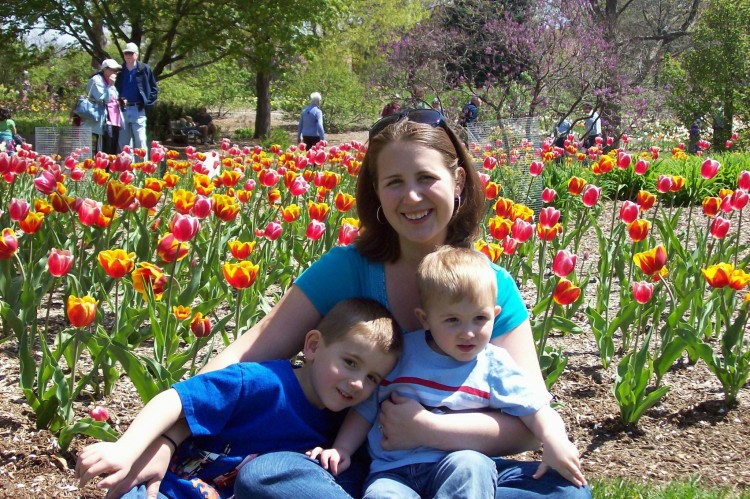 woman and two boys sitting in field of flowers