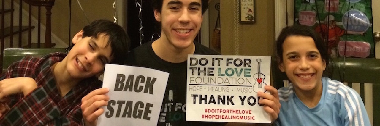 Mom Sends Blind Son to Weekend of Concerts for His 16th Birthday three boys with middle boy holding up two signs