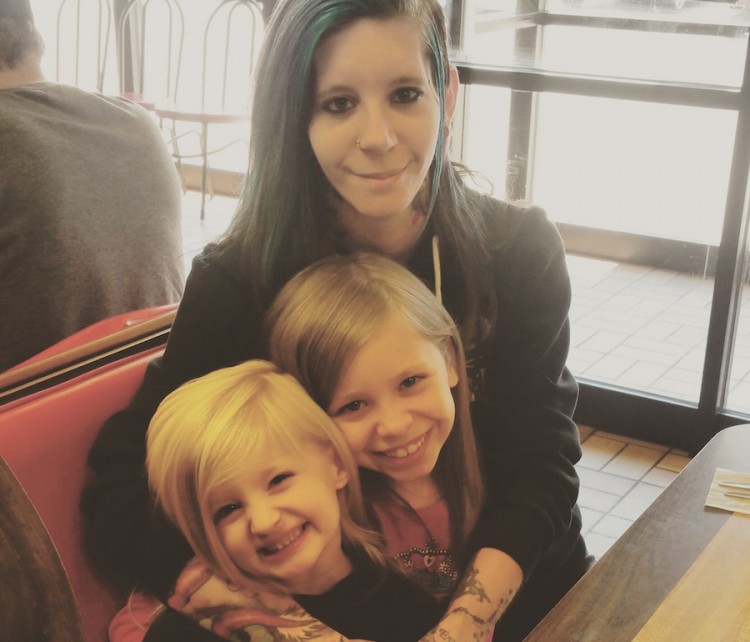 woman with arms around two girls sitting at a table