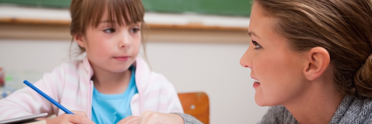 How Teachers Can Tell Parents They Suspect a Child Has Special Needs Schoolgirl writing while her teacher is talking.
