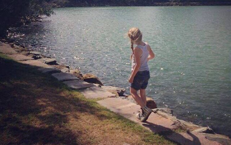 young girl walking along the edge of a lake