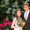 bride and groom posing together in front of flowers