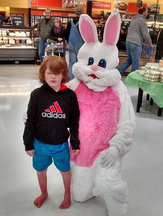 boy with EM standing next to easter bunny in grocery store