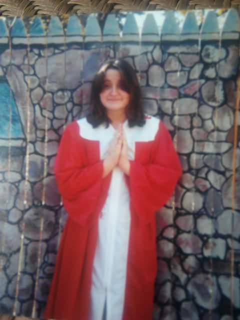 woman in red and white robe holding her hands up in prayer