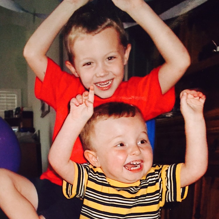 two brothers with their arms raised and smiling