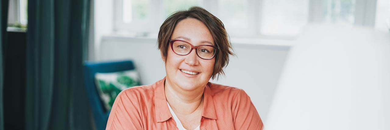 Flying Under the Radar as an Autistic Adult With ADHD Woman with short hair and glasses at home