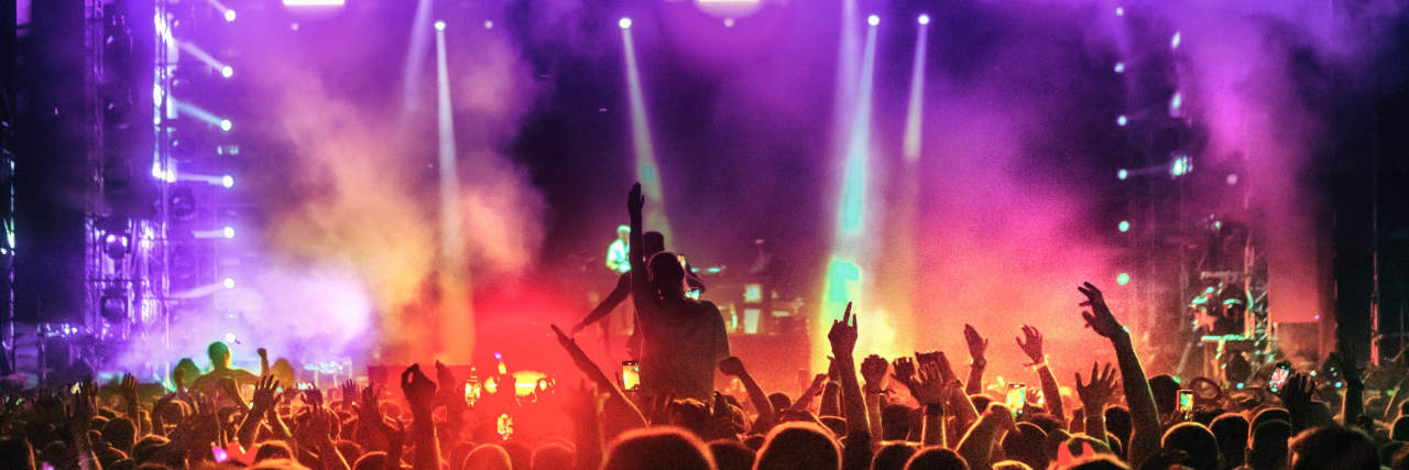 Tips for Going to Concerts When You Have Anxiety large group of people at a concert with purple and red colored smoke and lights
