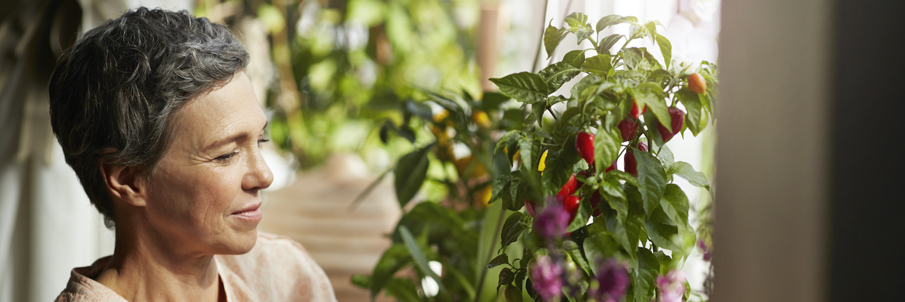 8 Small Acts of Kindness to Do for Someone in Need Woman with short hair arranging plants with flowers inside