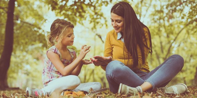 Mother and young daughter outside under tree