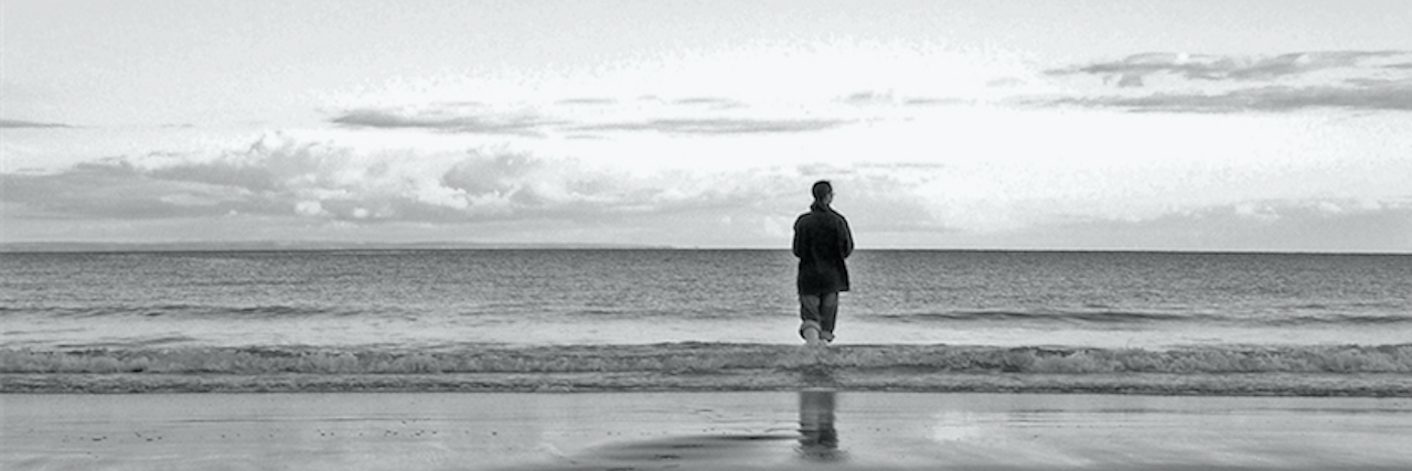 lone man standing next to the ocean