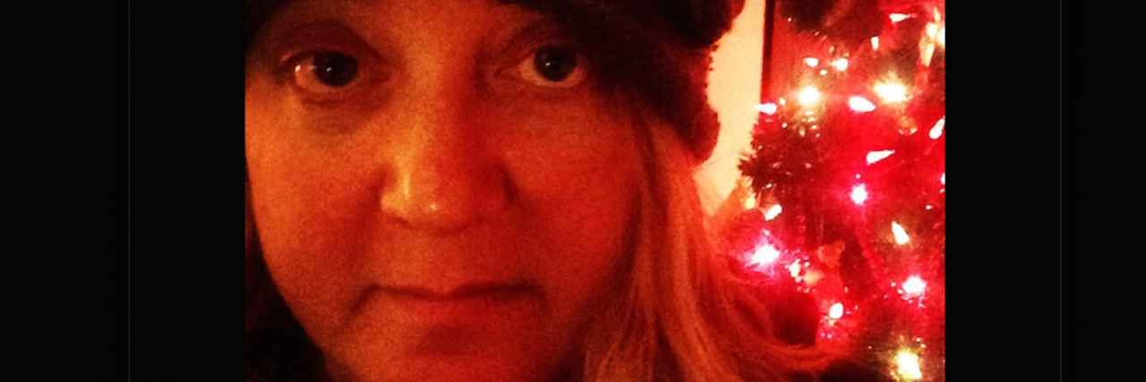 Parenting With an Anxiety Disorder Selfie of the author wearing a black beanie in front of red Christmas lights