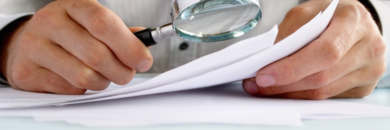 Pursuing a Diagnosis for Your Child's Rare Disease Businessman looking through a magnifying glass to documents